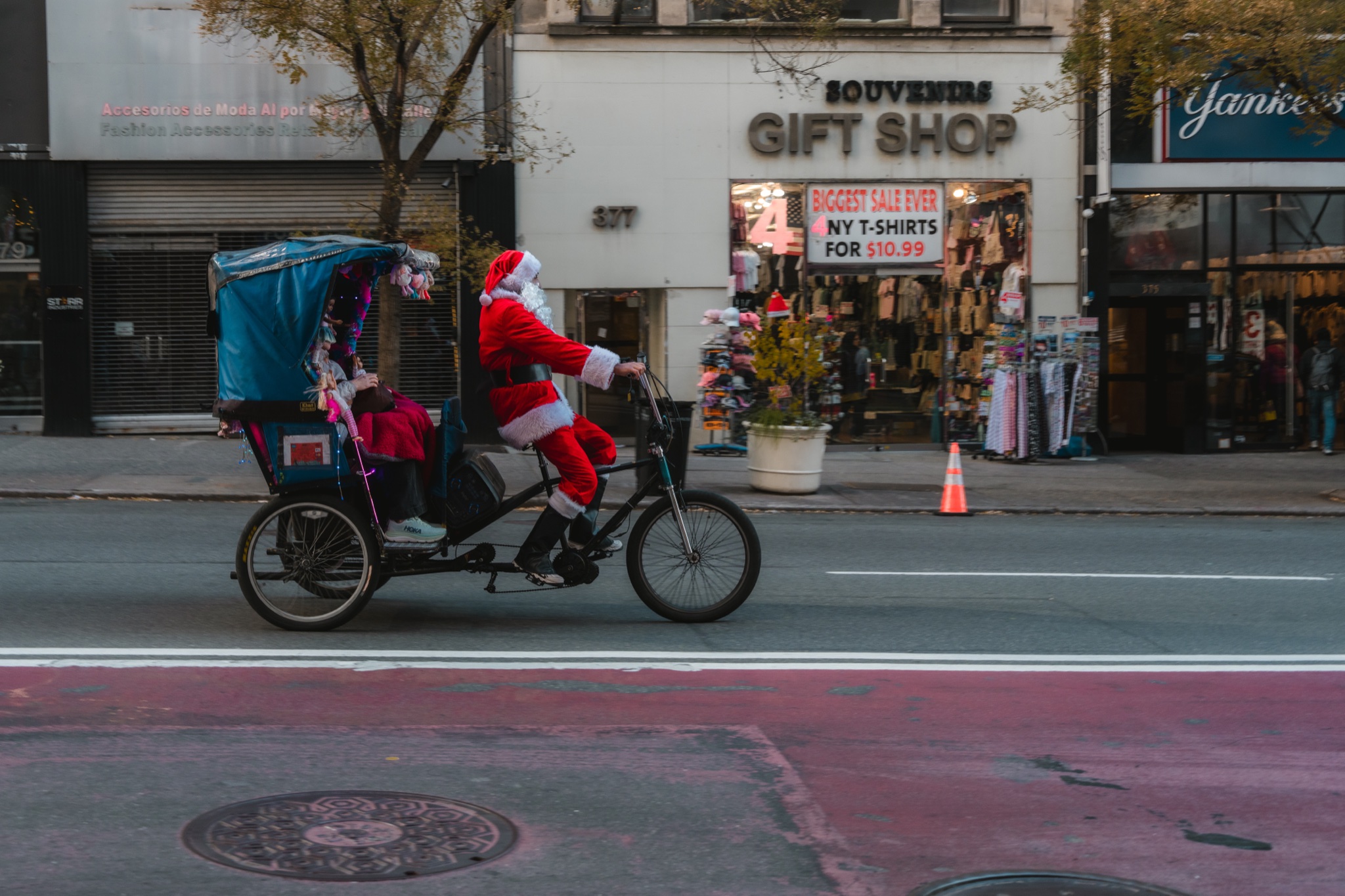 Santa pedaling a pedicab past a Manhattan gift shop
